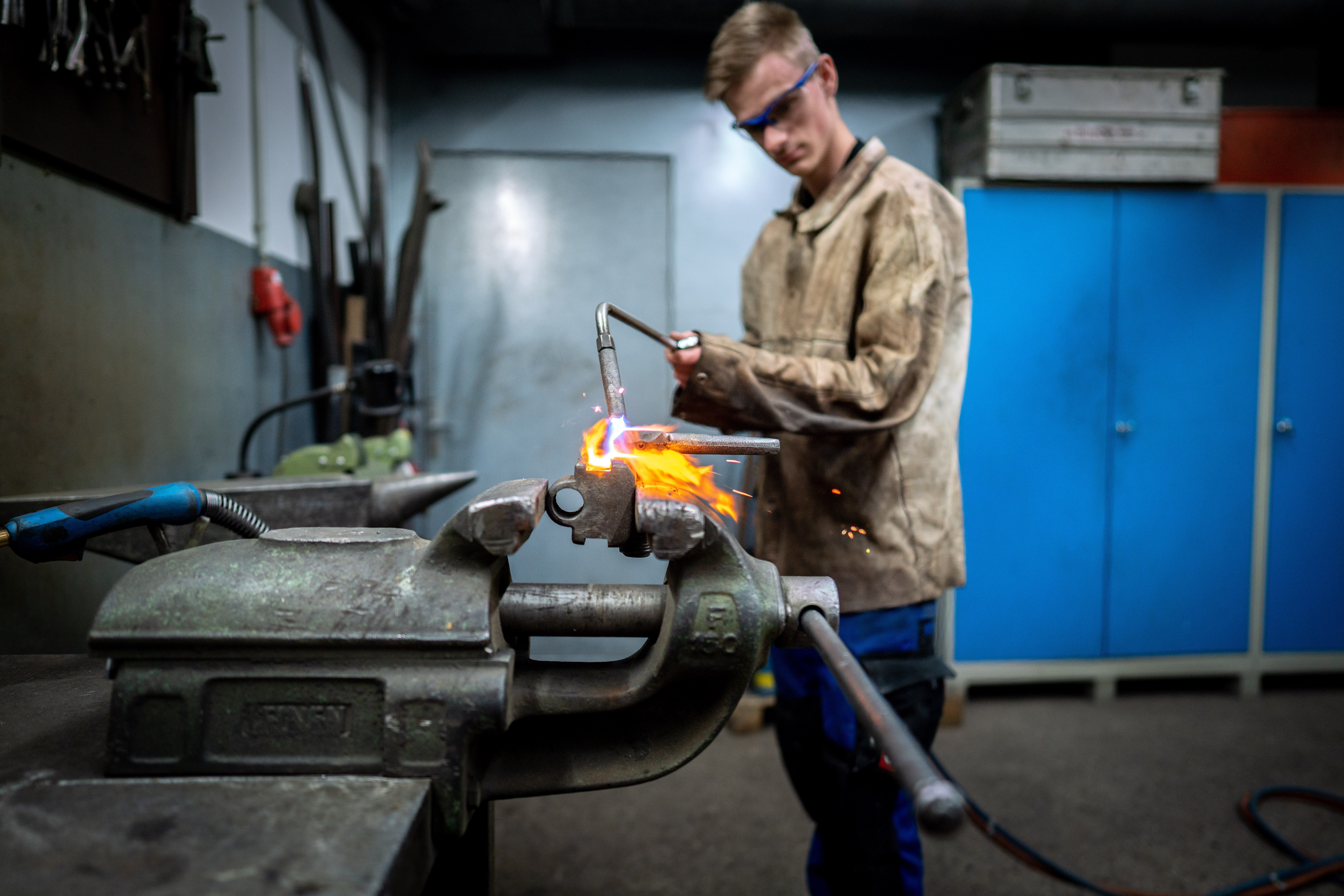 Werkstattarbeit an der Werkbank – Metallteil wird mit dem Brenner bearbeitet